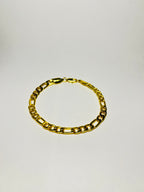 Rövid hosszú láncszemes arany karlánc letisztult, világos háttéren, minimalista kompozícióban.