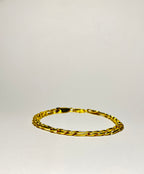 Rövid hosszú láncszemes arany karlánc letisztult, világos háttéren, minimalista kompozícióban.