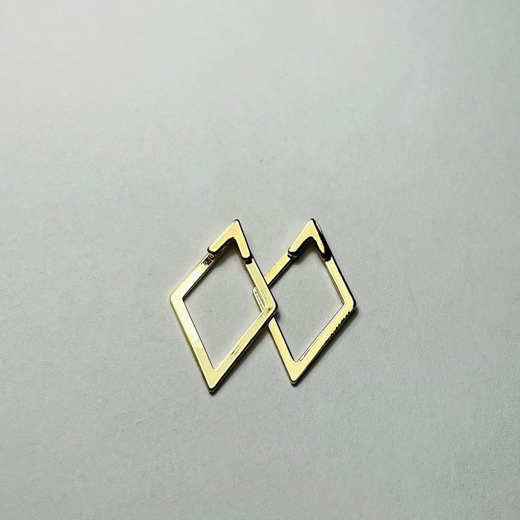 Aranyozott rombusz alakú fülbevaló pár fehér háttéren, letisztult és elegáns megjelenéssel.