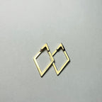 Aranyozott rombusz alakú fülbevaló pár fehér háttéren, letisztult és elegáns megjelenéssel.