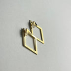 Aranyozott rombusz alakú fülbevaló pár fehér háttéren, letisztult és elegáns megjelenéssel.