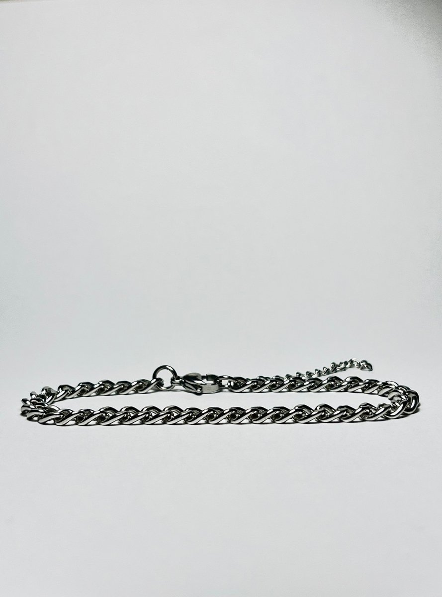 Rövid láncszemes arany nyaklánc és hozzá illő láncszemes karlánc fehér háttéren, letisztult és elegáns megjelenéssel.