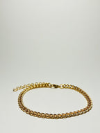 Aranyozott rövid láncszemes nyaklánc fehér háttéren, fényes felülettel és letisztult, elegáns megjelenéssel.