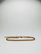 Aranyozott rövid láncszemes nyaklánc fehér háttéren, fényes felülettel és letisztult, elegáns megjelenéssel.