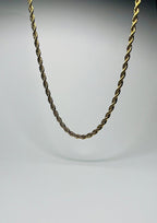 Aranyozott csavart láncszemes nyaklánc fehér háttéren, fényes felülettel és letisztult, elegáns megjelenéssel.