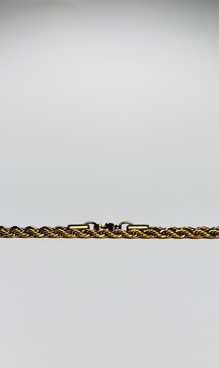 Aranyozott csavart láncszemes nyaklánc fehér háttéren, fényes felülettel és letisztult, elegáns megjelenéssel.