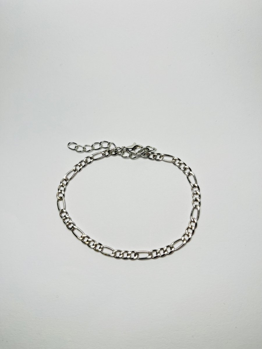 Aranyozott hosszú-rövid láncszemes karlánc fehér háttéren, fényes felülettel és letisztult, elegáns megjelenéssel.