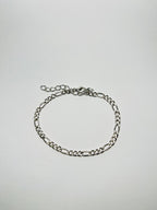 Aranyozott hosszú-rövid láncszemes karlánc fehér háttéren, fényes felülettel és letisztult, elegáns megjelenéssel.