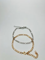 Aranyozott hosszú-rövid láncszemes karlánc fehér háttéren, fényes felülettel és letisztult, elegáns megjelenéssel.