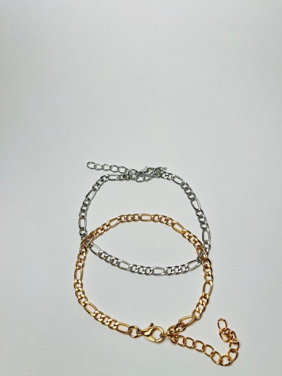 Aranyozott hosszú-rövid láncszemes karlánc fehér háttéren, fényes felülettel és letisztult, elegáns megjelenéssel.