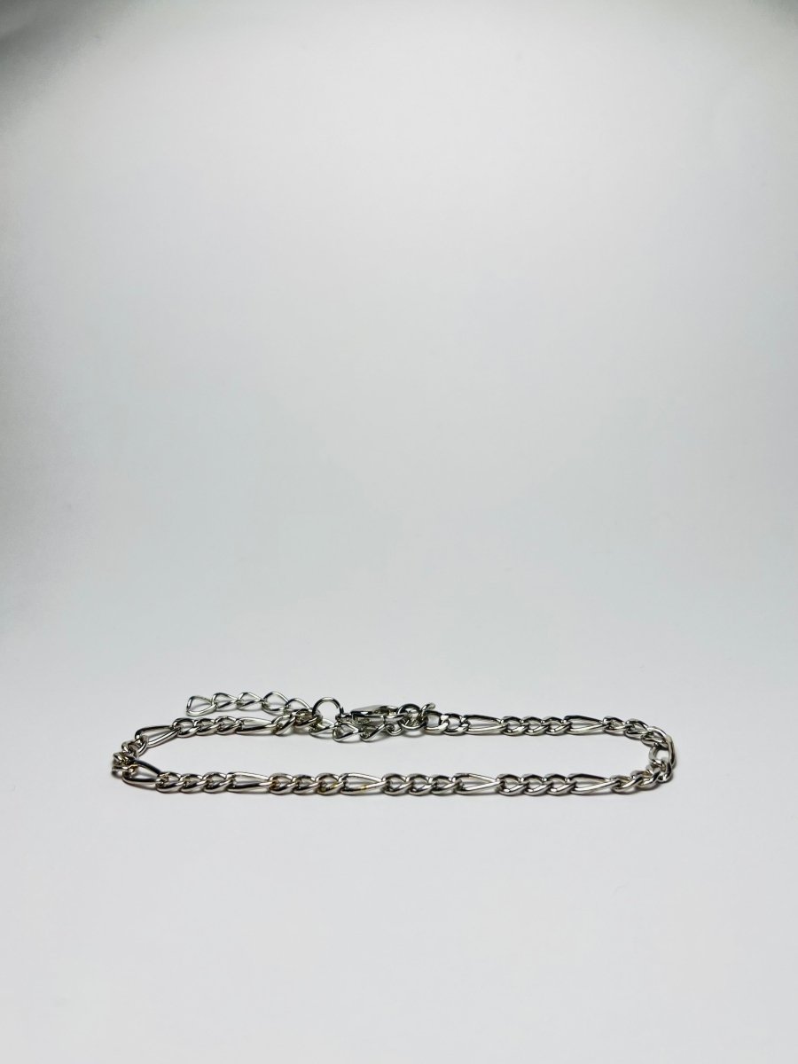 Aranyozott hosszú-rövid láncszemes karlánc fehér háttéren, fényes felülettel és letisztult, elegáns megjelenéssel.