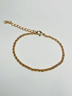 Aranyozott csavart láncszemes karlánc fehér háttéren, fényes felülettel és letisztult, elegáns megjelenéssel.