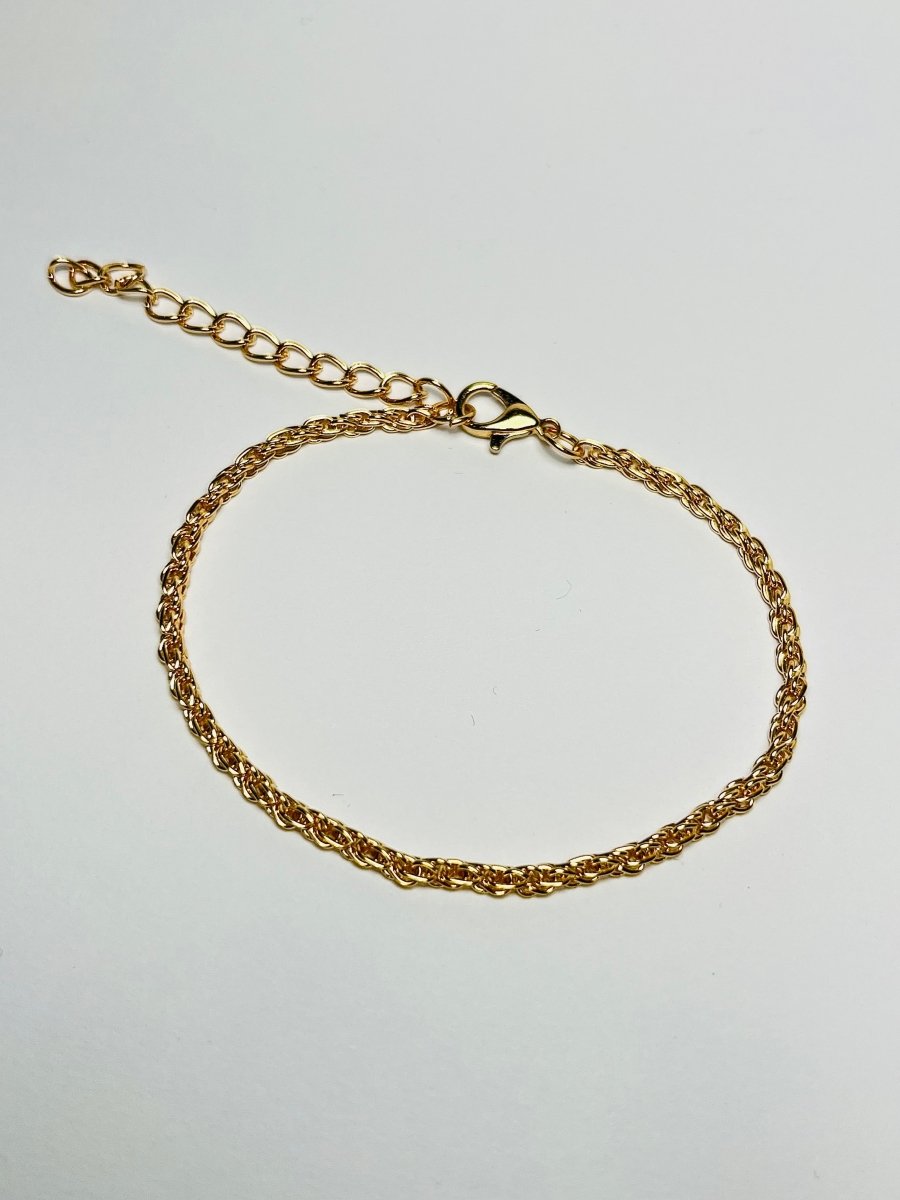 Aranyozott csavart láncszemes karlánc fehér háttéren, fényes felülettel és letisztult, elegáns megjelenéssel.