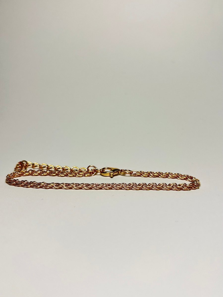 Aranyozott csavart láncszemes karlánc fehér háttéren, fényes felülettel és letisztult, elegáns megjelenéssel.