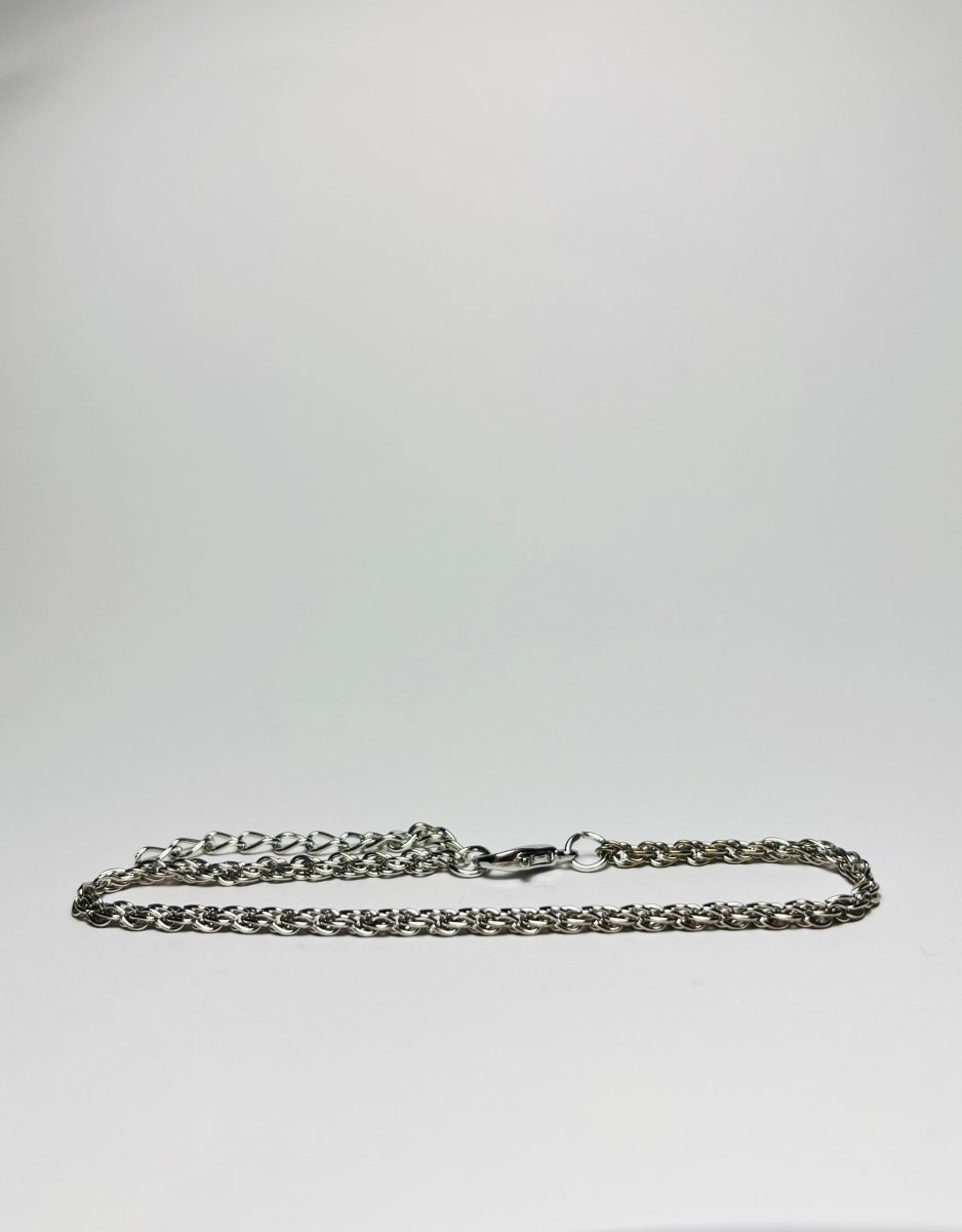 Aranyozott csavart láncszemes karlánc fehér háttéren, fényes felülettel és letisztult, elegáns megjelenéssel.