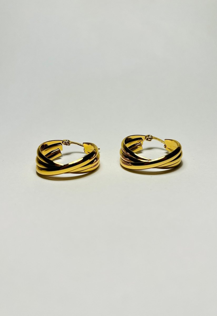 Aranyozott csavart karika fülbevaló pár fehér háttéren, fényes felülettel és elegáns, modern megjelenéssel.