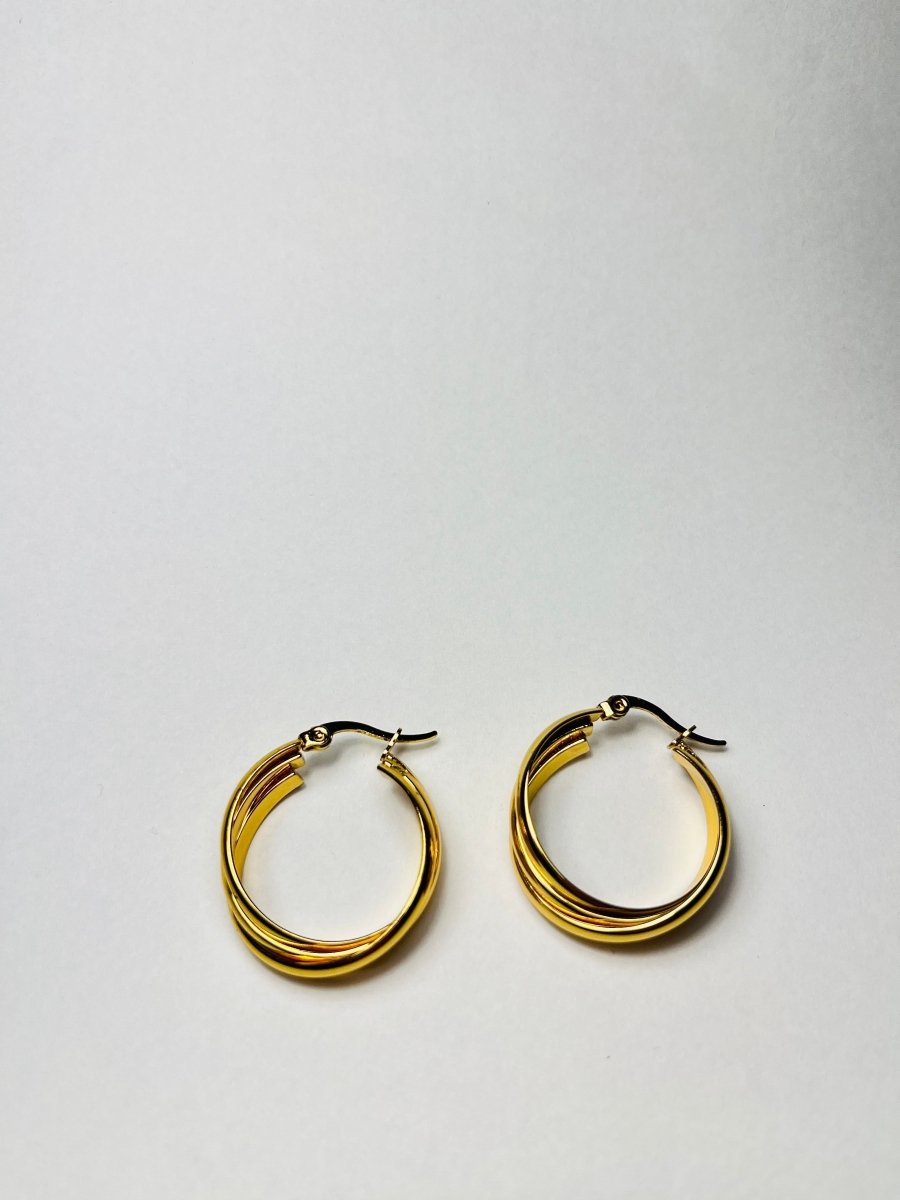 Aranyozott csavart karika fülbevaló pár fehér háttéren, fényes felülettel és elegáns, modern megjelenéssel.